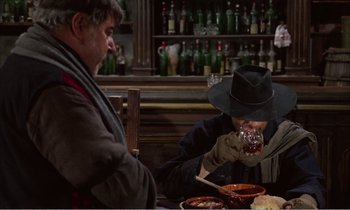 Movie still from “Django” (1966), directed by Sergio Corbucci – Two men sitting at a table with a plate of food; Medium shot, Over the shoulder angle