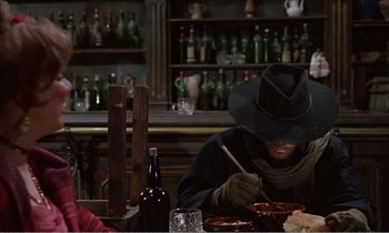 Movie still from “Django” (1966), directed by Sergio Corbucci – A man sitting at a table with a plate in front of him; Medium shot, High angle