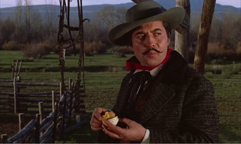 Movie still from “Django” (1966), directed by Sergio Corbucci – A man wearing a hat and holding a hot dog in his hand; Medium shot, Low angle
