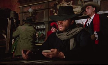 Movie still from “Django” (1966), directed by Sergio Corbucci – A man in a cowboy hat is holding a cell phone; Medium shot, Low angle