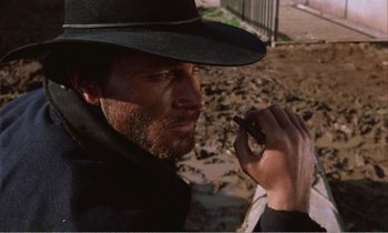 Movie still from “Django” (1966), directed by Sergio Corbucci – A man wearing a hat and holding a cell phone to his ear; Close Up shot, Low angle
