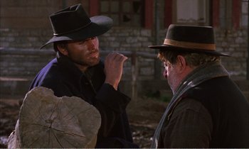 Movie still from “Django” (1966), directed by Sergio Corbucci – A man in a cowboy hat is talking to another man; Medium shot, Over the shoulder angle