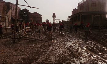 Movie still from “Django” (1966), directed by Sergio Corbucci – A group of people in a muddy area with buildings in the background; Wide shot, High angle