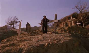 Movie still from “Django” (1966), directed by Sergio Corbucci – A man standing next to a bunch of grave markers; Wide shot, Low angle