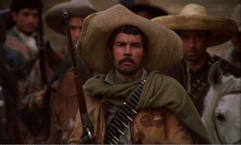 Movie still from “Django” (1966), directed by Sergio Corbucci – A man with a hat and a rifle in front of a group of men; Medium shot, Low angle