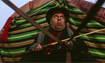 Movie still from “Django” (1966), directed by Sergio Corbucci – A man with a hat holding a large umbrella; Medium shot, Low angle