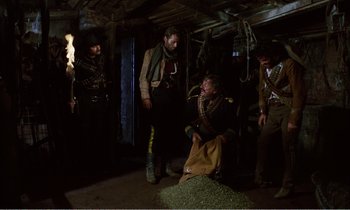 Movie still from “Django” (1966), directed by Sergio Corbucci – A group of men standing around a woman in a room; Wide shot, Low angle