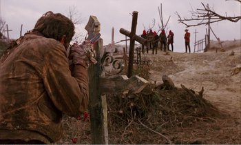Movie still from “Django” (1966), directed by Sergio Corbucci – A man standing next to a cross on a dirt hill; Wide shot, Low angle