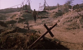 Movie still from “Django” (1966), directed by Sergio Corbucci – A man standing on a dirt hill next to crosses; Extreme Wide shot, High angle