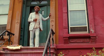 Movie still from “Do the Right Thing” (1989), directed by Spike Lee – A man standing on the steps of a building; Wide shot, Low angle