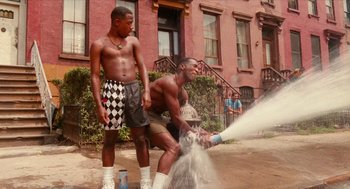 Movie still from “Do the Right Thing” (1989), directed by Spike Lee – Two young men standing next to a fire hydrant spraying water; Wide shot, Low angle