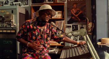 Movie still from “Do the Right Thing” (1989), directed by Spike Lee – An older man wearing a colorful shirt and a hat; Medium shot, High angle