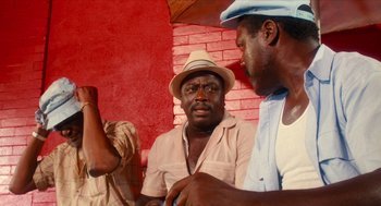 Movie still from “Do the Right Thing” (1989), directed by Spike Lee – Two men are talking in front of a brick wall; Medium shot, Low angle