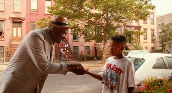 Movie still from “Do the Right Thing” (1989), directed by Spike Lee – An older man and a young boy are shaking hands; Medium shot, Over the shoulder angle