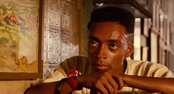 Movie still from “Do the Right Thing” (1989), directed by Spike Lee – A man with a red bracelet is leaning on his arm; Close Up shot, Low angle