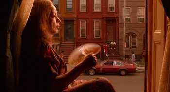 Movie still from “Do the Right Thing” (1989), directed by Spike Lee – A woman sitting on the side of the road holding a fan; Wide shot, Low angle