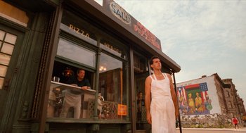 Movie still from “Do the Right Thing” (1989), directed by Spike Lee – A man standing in front of a pizza shop; Wide shot, Low angle