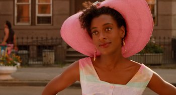 Movie still from “Do the Right Thing” (1989), directed by Spike Lee – A woman wearing a large pink hat and looking to her left; Close Up shot, Low angle