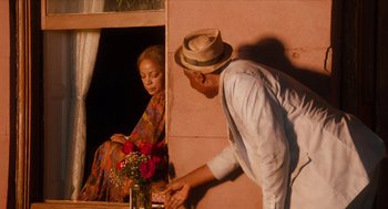 Movie still from “Do the Right Thing” (1989), directed by Spike Lee – An older man and a young woman in front of a window; Medium shot, Over the shoulder angle
