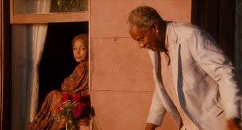 Movie still from “Do the Right Thing” (1989), directed by Spike Lee – An older man and a young woman are looking out of a window; Medium shot, Over the shoulder angle