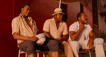 Movie still from “Do the Right Thing” (1989), directed by Spike Lee – A group of men sitting next to each other on a bench; Medium shot, Low angle