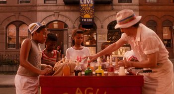 Movie still from “Do the Right Thing” (1989), directed by Spike Lee – A group of young people sitting at a table with drinks; Medium shot, Over the shoulder angle