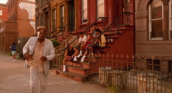 Movie still from “Do the Right Thing” (1989), directed by Spike Lee – A group of people sitting on the steps of a building; Wide shot, Low angle