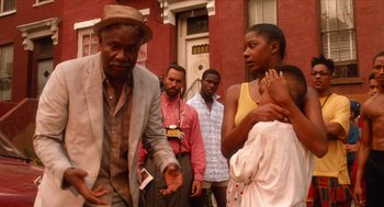 Movie still from “Do the Right Thing” (1989), directed by Spike Lee – A group of people standing in front of a brick building; Medium shot, Low angle