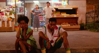 Movie still from “Do the Right Thing” (1989), directed by Spike Lee – A group of people sitting on the ground in front of a store; Wide shot, Low angle