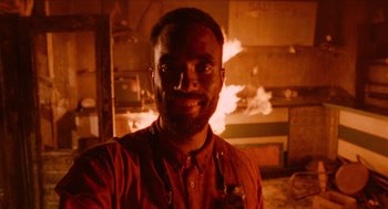 Movie still from “Do the Right Thing” (1989), directed by Spike Lee – A man in a red shirt is in front of a fire; Close Up shot, Low angle