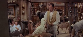 Movie still from “Doctor Dolittle” (1967), directed by Richard Fleischer – A man standing next to a table with a bird on top of it; Medium shot, Low angle