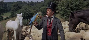 Movie still from “Doctor Dolittle” (1967), directed by Richard Fleischer – A man in a top hat holding a parrot in his hand; Medium shot, Low angle