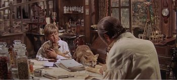 Movie still from “Doctor Dolittle” (1967), directed by Richard Fleischer – A woman sitting at a table with a dog and two children; Medium shot, High angle