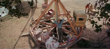 Movie still from “Doctor Dolittle” (1967), directed by Richard Fleischer – A man standing in front of an amusement park ride; Wide shot, High angle