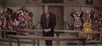 Movie still from “Doctor Dolittle” (1967), directed by Richard Fleischer – A man standing in front of a group of people in a courtroom; Wide shot, Low angle