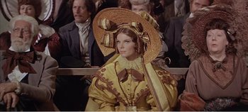 Movie still from “Doctor Dolittle” (1967), directed by Richard Fleischer – A woman in a yellow dress with a hat on her head; Medium shot, Over the shoulder angle