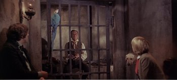 Movie still from “Doctor Dolittle” (1967), directed by Richard Fleischer – A man sitting in front of a bird in a jail cell; Medium shot, Low angle