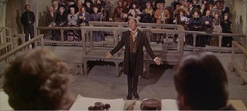 Movie still from “Doctor Dolittle” (1967), directed by Richard Fleischer – A man in a suit and tie standing in front of an audience; Medium shot, High angle