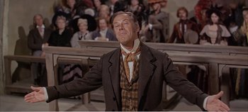 Movie still from “Doctor Dolittle” (1967), directed by Richard Fleischer – A man in a suit and tie standing in front of a group of people; Medium shot, Low angle