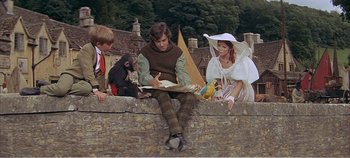 Movie still from “Doctor Dolittle” (1967), directed by Richard Fleischer – A group of people sitting on top of a stone wall; Medium shot, High angle