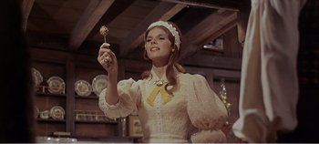 Movie still from “Doctor Dolittle” (1967), directed by Richard Fleischer – A woman in a white dress holding a stick of food; Medium shot, Low angle