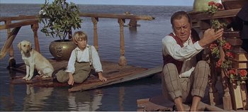 Movie still from “Doctor Dolittle” (1967), directed by Richard Fleischer – A man and a boy sitting on a raft in the middle of a lake; Wide shot, High angle