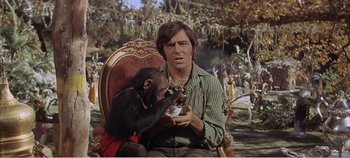 Movie still from “Doctor Dolittle” (1967), directed by Richard Fleischer – A man sitting in a chair holding a monkey; Medium shot, Over the shoulder angle