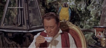 Movie still from “Doctor Dolittle” (1967), directed by Richard Fleischer – A man sitting in a chair with a parrot on his shoulder; Medium shot, Low angle