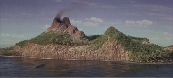 Movie still from “Doctor Dolittle” (1967), directed by Richard Fleischer – A large rock formation near a body of water; Extreme Wide shot, High angle