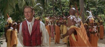 Movie still from “Doctor Dolittle” (1967), directed by Richard Fleischer – A group of people in costumes walking on a beach; Medium shot, Over the shoulder angle