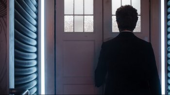 Movie still from “Doctor Who: The Husbands of River Song” (2015) – A man standing in front of an open front door; Medium shot, Over the shoulder angle