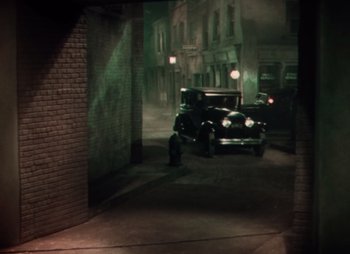 Movie still from “Doctor X” (1932), directed by Michael Curtiz – An old car is parked in a dark alley; Extreme Wide shot, High angle