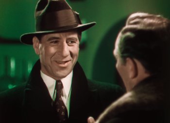 Movie still from “Doctor X” (1932), directed by Michael Curtiz – A man wearing a hat and a suit talking to another man wearing a hat; Close Up shot, Over the shoulder angle
