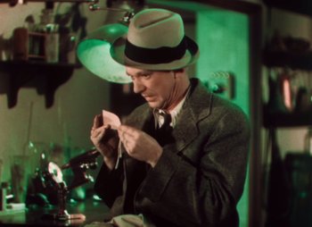 Movie still from “Doctor X” (1932), directed by Michael Curtiz – A man wearing a hat and a suit and tie; Close Up shot, High angle